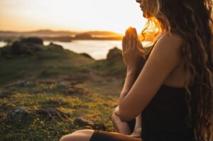 A young woman meditating and contemplating her addiction recovery outdoors.